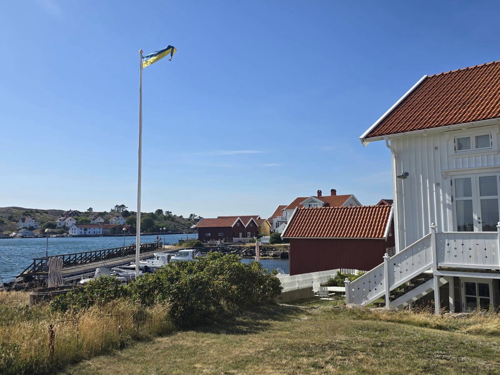 Svensk flagga, vitt trähus och hamn på Orust